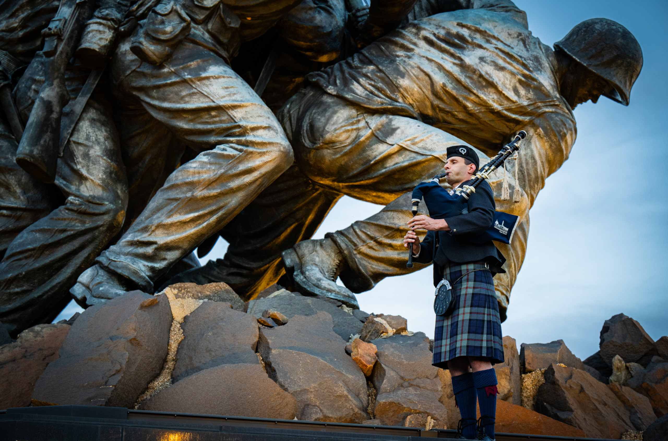 Bagpiper in traditional attire performs at a war memorial to honor military service and sacrifice.
